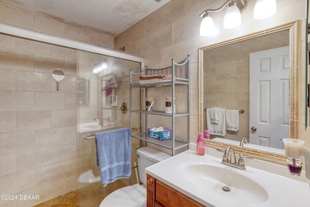 bathroom featuring vanity, a textured ceiling, a shower with door, tile walls, and toilet