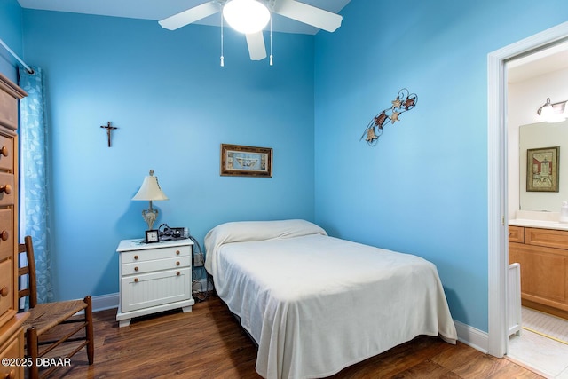 bedroom featuring dark wood-style floors, a ceiling fan, ensuite bathroom, and baseboards