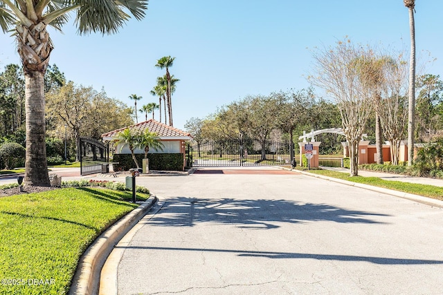 view of street with a gated entry, sidewalks, curbs, and a gate