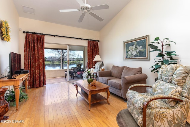 living area featuring visible vents, light wood-style flooring, high vaulted ceiling, and a ceiling fan