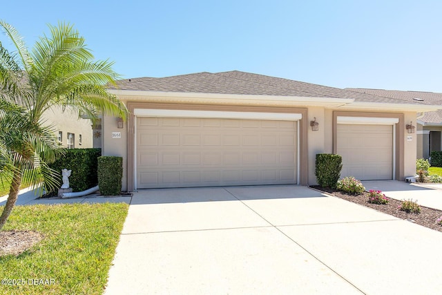 view of front facade with stucco siding, concrete driveway, an attached garage, and a shingled roof