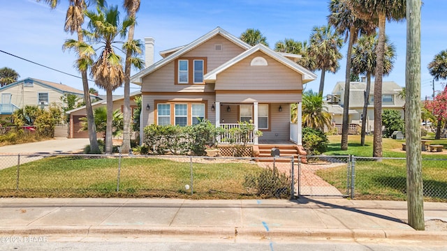 view of front facade with a fenced front yard, covered porch, driveway, and a front lawn