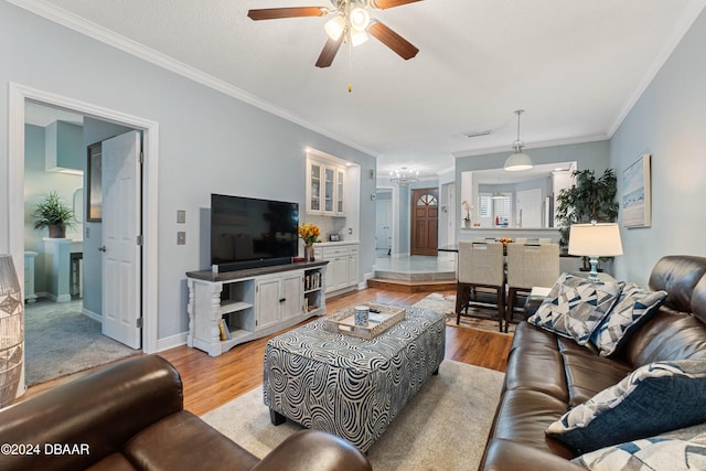 living room with ceiling fan, crown molding, and light hardwood / wood-style flooring