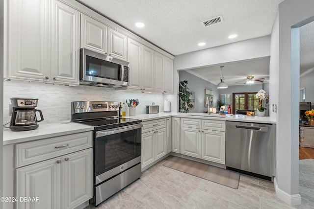 kitchen featuring tasteful backsplash, a textured ceiling, stainless steel appliances, sink, and white cabinetry