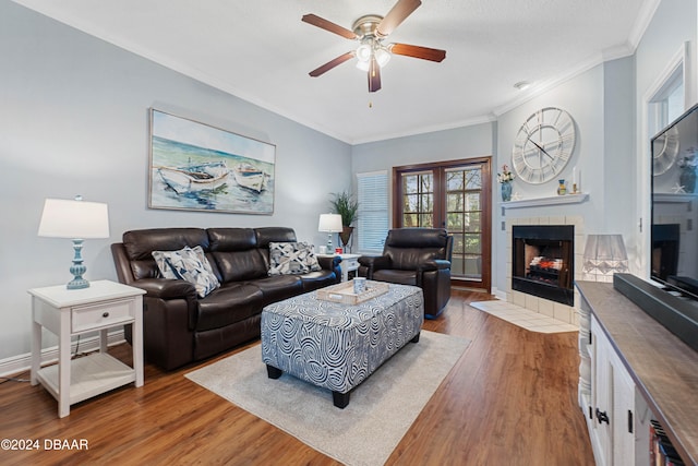 living room with a fireplace, wood-type flooring, ceiling fan, and ornamental molding