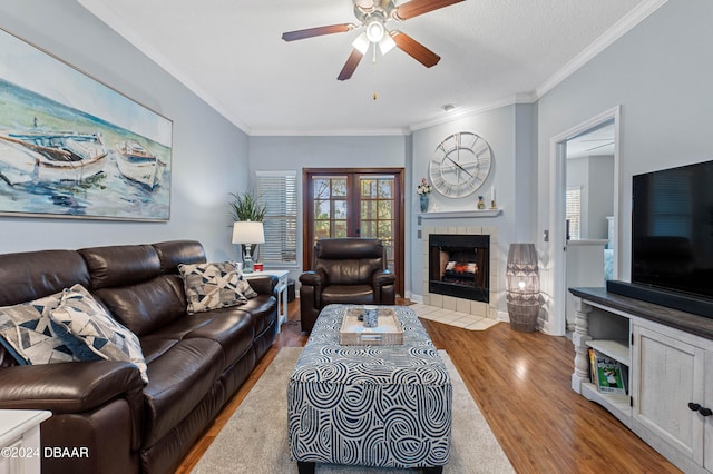 living room featuring crown molding, ceiling fan, a textured ceiling, a fireplace, and wood-type flooring