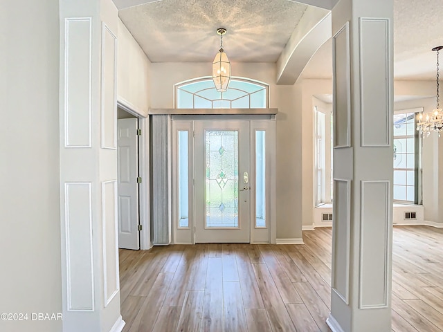 46 Coquina Point Dr, Ormond Beach, FL 32174 - entryway featuring light hardwood / wood-style floors, a textured ceiling, and a notable chandelier