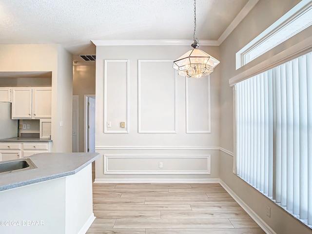 46 Coquina Point Dr, Ormond Beach, FL 32174 - kitchen featuring light hardwood / wood-style floors, an inviting chandelier, white cabinets, hanging light fixtures, and a textured ceiling