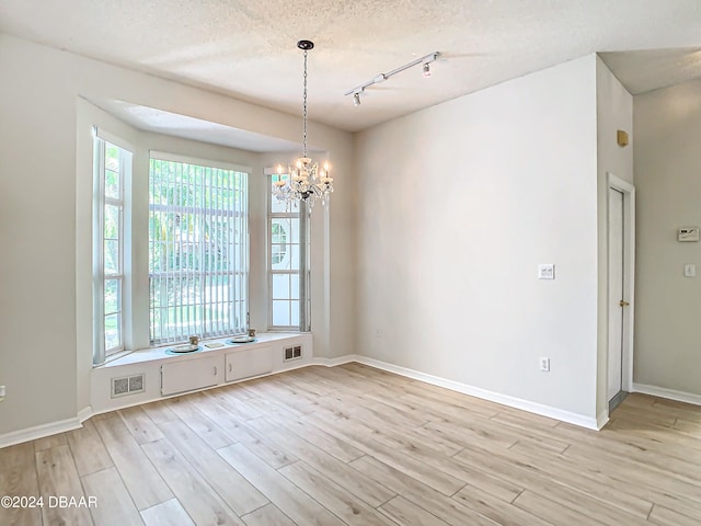 46 Coquina Point Dr, Ormond Beach, FL 32174 - spare room with light wood-type flooring, an inviting chandelier, and a textured ceiling