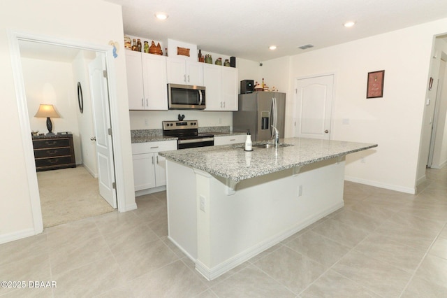 1313 Middle Lake Dr, Ormond Beach, FL 32174 - kitchen with stainless steel appliances, an island with sink, white cabinetry, a sink, and light tile patterned floors