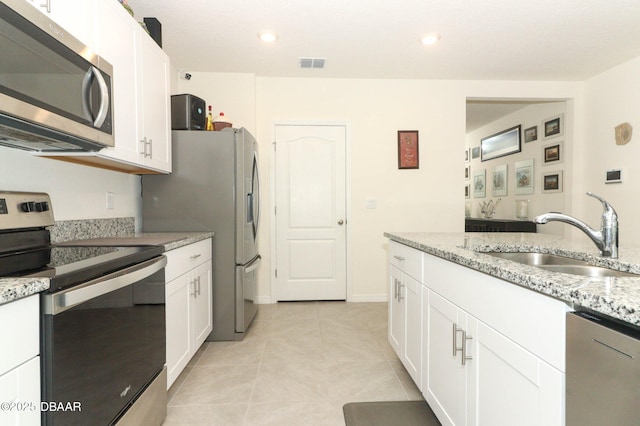 1313 Middle Lake Dr, Ormond Beach, FL 32174 - kitchen featuring appliances with stainless steel finishes, a sink, white cabinetry, light tile patterned flooring, and recessed lighting