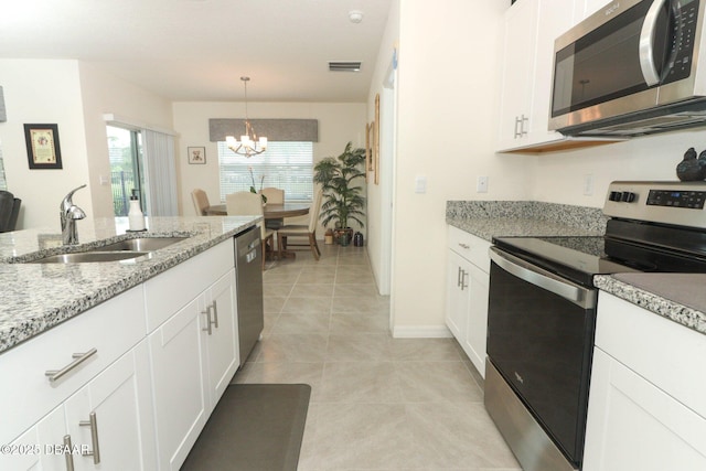 1313 Middle Lake Dr, Ormond Beach, FL 32174 - kitchen featuring appliances with stainless steel finishes, a sink, a chandelier, and white cabinets