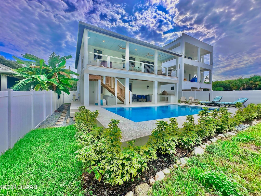 back of house featuring a patio area, a fenced in pool, and a balcony