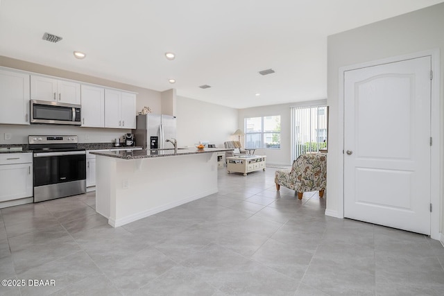 58 Bella Oaks Dr, Port Orange, FL 32129 - kitchen with appliances with stainless steel finishes, dark stone counters, an island with sink, white cabinetry, and recessed lighting