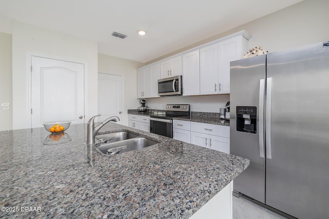 58 Bella Oaks Dr, Port Orange, FL 32129 - kitchen with stainless steel appliances, white cabinets, dark stone counters, and recessed lighting