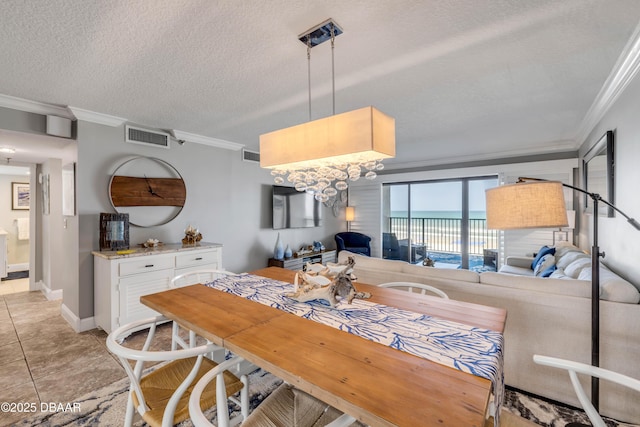 5499 S Atlantic Ave, New Smyrna Beach, FL 32169 - dining area featuring ornamental molding, light tile patterned floors, a textured ceiling, and a chandelier