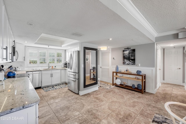 5499 S Atlantic Ave, New Smyrna Beach, FL 32169 - kitchen with a textured ceiling, stainless steel appliances, white cabinets, light stone countertops, and ornamental molding