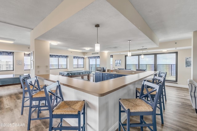 5499 S Atlantic Ave, New Smyrna Beach, FL 32169 - kitchen featuring wood finished floors, a kitchen breakfast bar, pendant lighting, and a peninsula