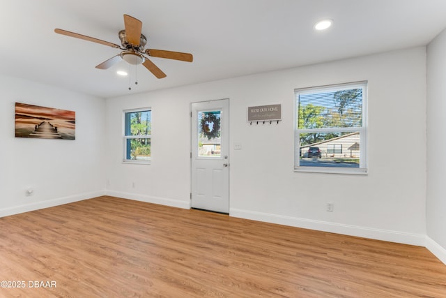 empty room with a wealth of natural light, recessed lighting, light wood-style flooring, and baseboards