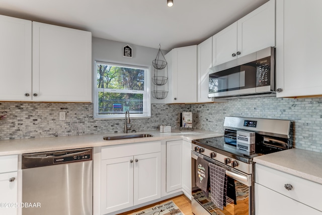 kitchen featuring a sink, stainless steel appliances, white cabinets, and light countertops