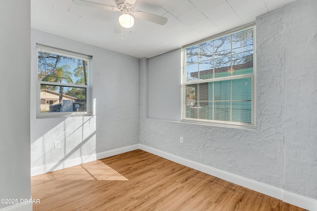 unfurnished room with baseboards, a ceiling fan, a textured wall, and wood finished floors