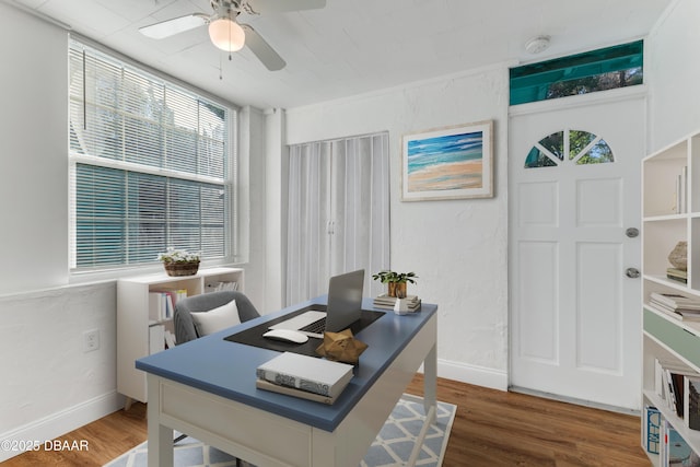 office featuring a textured wall, baseboards, ceiling fan, and wood finished floors