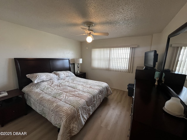 bedroom with ceiling fan, light wood-type flooring, and a textured ceiling