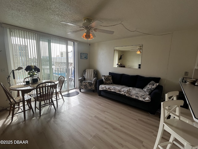 living room with ceiling fan, a textured ceiling, and light hardwood / wood-style flooring