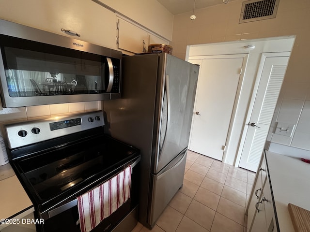 kitchen with white cabinetry, light tile patterned floors, and stainless steel appliances