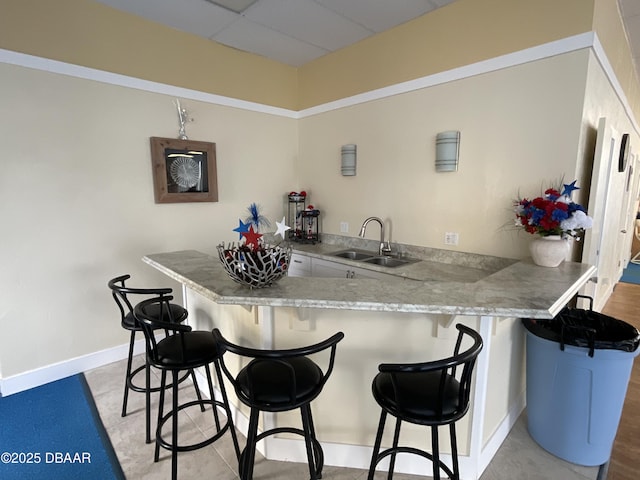 kitchen featuring a drop ceiling, sink, kitchen peninsula, and a breakfast bar area