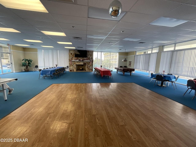 recreation room with carpet flooring, a stone fireplace, a drop ceiling, and pool table