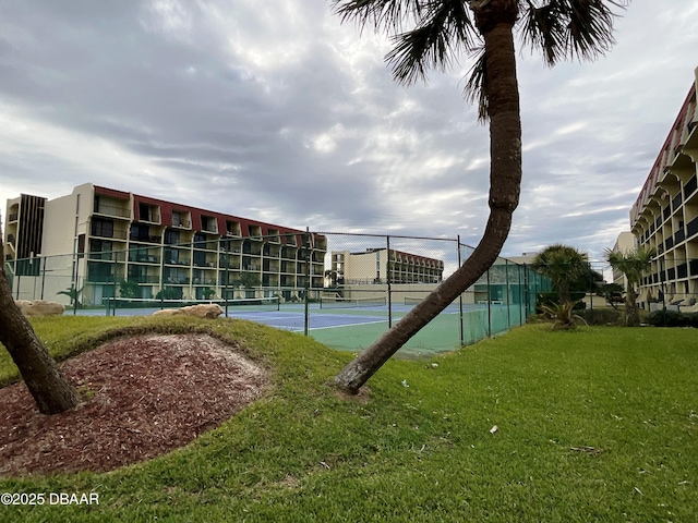 view of tennis court featuring a yard