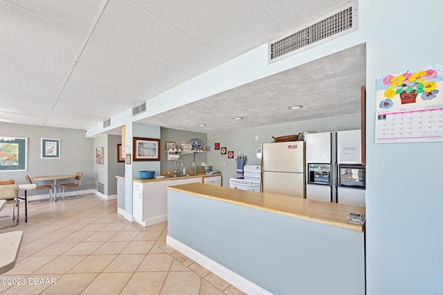 3600 S Ocean Shore Blvd # 111, Flagler Beach, FL 32136 - kitchen featuring a sink, white appliances, visible vents, light countertops, and light tile patterned floors