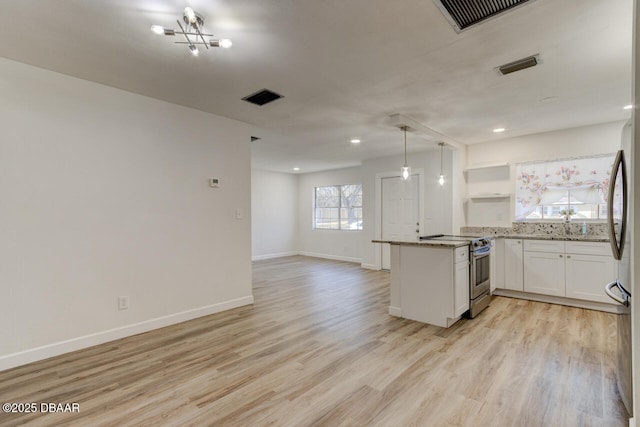 kitchen with pendant lighting, white cabinets, kitchen peninsula, stainless steel appliances, and light wood-type flooring