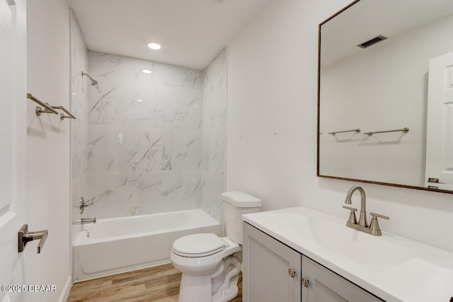 full bathroom featuring hardwood / wood-style flooring, tiled shower / bath, vanity, and toilet