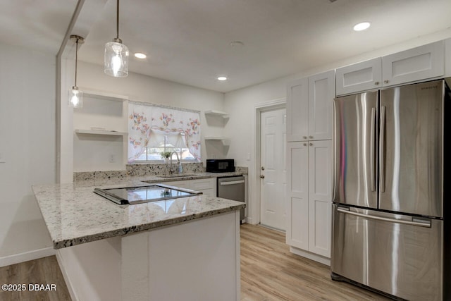 kitchen with black appliances, sink, white cabinets, hanging light fixtures, and kitchen peninsula