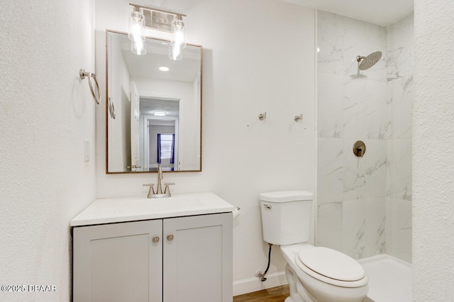 bathroom with vanity, a tile shower, and toilet