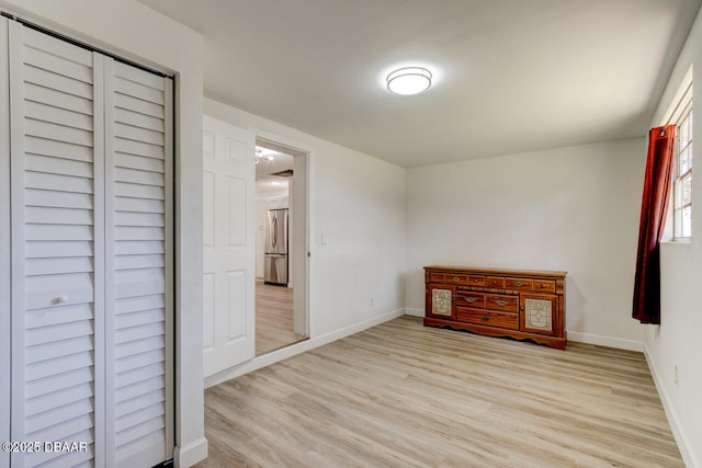 unfurnished bedroom with stainless steel refrigerator, a closet, and light hardwood / wood-style flooring