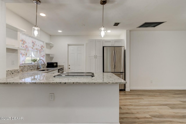 kitchen featuring white cabinetry, pendant lighting, stainless steel refrigerator, and kitchen peninsula