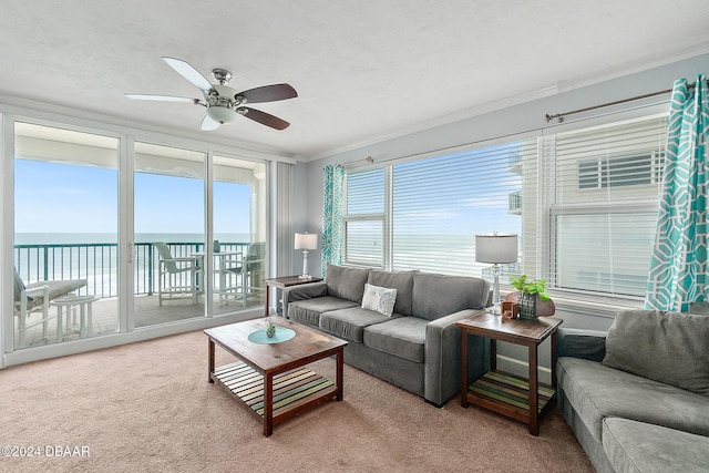 living room with carpet floors, ceiling fan, a water view, and ornamental molding