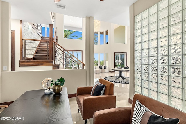 sitting room with stairway, a towering ceiling, and visible vents