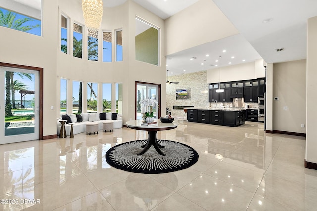 foyer with plenty of natural light, baseboards, a high ceiling, and a chandelier