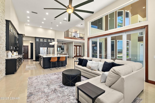 living area with a high ceiling, a ceiling fan, recessed lighting, and visible vents