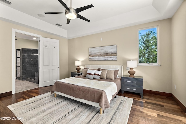 bedroom with baseboards, a raised ceiling, wood finished floors, and visible vents