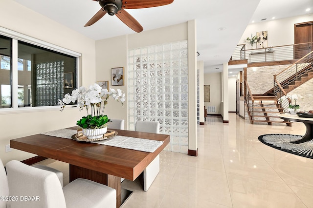 dining space featuring a ceiling fan, visible vents, light tile patterned floors, baseboards, and stairs