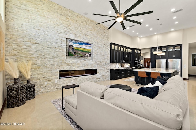 living room with ceiling fan, a high ceiling, recessed lighting, light tile patterned floors, and visible vents