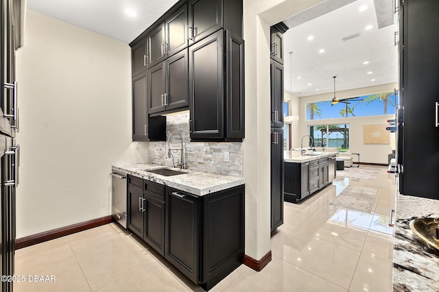 kitchen featuring decorative backsplash, a ceiling fan, stainless steel dishwasher, a sink, and dark cabinets