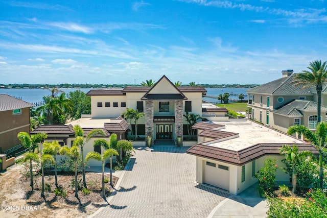 view of front of house featuring a water view, stucco siding, decorative driveway, and stone siding