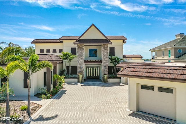 view of front of house with french doors, stucco siding, decorative driveway, and stone siding