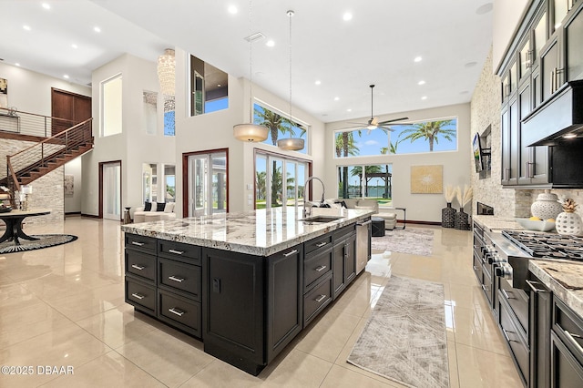 kitchen featuring ceiling fan, a large island, a sink, dark cabinetry, and recessed lighting